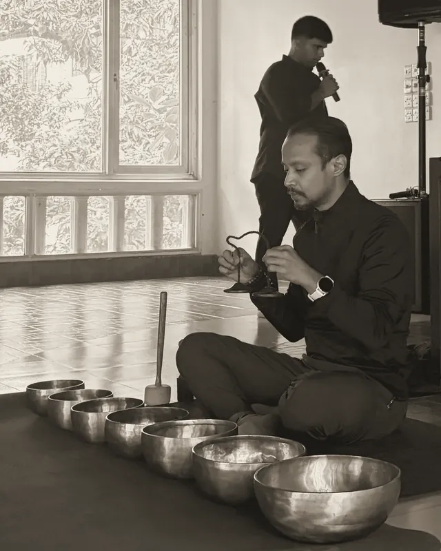 Ishtiaque listening as he sounds a pair of tingsha cymbals above the bowls